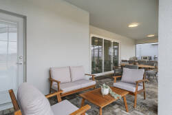 Relax on a covered patio with a round dining table, cozy outdoor seating, sliding glass doors, and peaceful green views, perfect for meals and family moments outside.