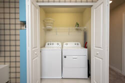 Experience the convenience of a spacious washer and dryer discreetly set behind double doors in this practical laundry nook, where the bright, airy atmosphere and warm lighting enhance your stay and functionality.