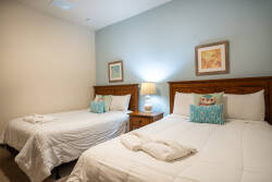Enjoy restful nights in this cozy bedroom featuring two comfy beds with soft white linens and vibrant aqua pillows. The warm wooden furniture and calming blue walls create a soothing ambiance for unwinding after your adventures.