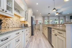 Enjoy a beautifully designed kitchen with creamy cabinets, sleek granite countertops, and a textured mosaic tile backsplash, all bathed in natural light that inspires your culinary creativity in a vibrant atmosphere.