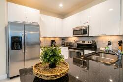 Discover this stylish kitchen with elegant white cabinets and striking dark granite countertops, ideal for meal prep and casual breakfasts.