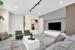 Experience a modern living area with a cozy gray sectional and a stylish white coffee table perfect for relaxation. Track lighting accentuates the decor, while green chair accents bring a refreshing vibe to the space.