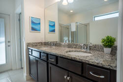 Relax in this bright bathroom with a spacious granite countertop and dark wood cabinetry for all your essentials. Stylish artwork and modern fixtures enhance the sophistication, while natural light adds a refreshing touch.
