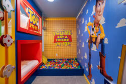 Experience a whimsical playroom bursting with joy and vibrant Toy Story-inspired decor. Cozy bunk beds in bright red alcoves create a fun sleeping nook, while a colorful ball pit promises endless laughter and creativity for all.