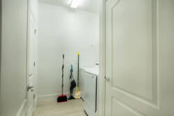 Discover the convenience of this laundry area, featuring a sleek washer and dryer surrounded by fresh, light-colored walls that enhance the spacious feel. Practical storage options and cleaning supplies ensure a seamless stay.
