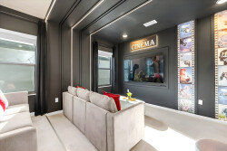 Step into your personal cinema, where plush gray seating and vibrant red accents create a cozy yet stylish atmosphere. The dramatic dark walls enhance the cinematic vibe, inviting you to enjoy movie nights with family and friends.