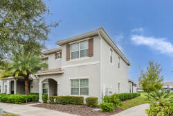 Experience a charming exterior with soft gray tones and lush landscaping, including palm trees, that create a welcoming atmosphere. Large windows let in natural light, filling this inviting home with a bright and airy ambiance.