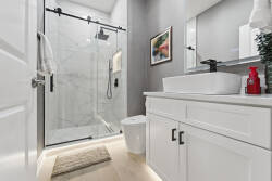 Enjoy a stylish bathroom with a sleek glass shower, modern black rainfall showerhead, and a chic vanity with a deep sink. The soft lighting enhances the contemporary design, offering a refreshing atmosphere during your stay.