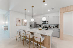 Enjoy the sleek kitchen featuring a spacious marble island and stylish gold-accented stools. The soft ambient lighting enhances the modern cabinetry, creating a warm and inviting atmosphere for preparing and enjoying meals.