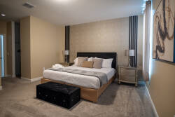 Unwind in this beautifully designed bedroom with a plush king-sized bed, soft linens, and textured pillows. The warm beige walls and elegant artwork create a refined ambiance, while natural light enhances the inviting atmosphere.