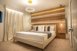 Experience serene nights in this thoughtfully designed bedroom featuring a plush bed with crisp white linens and a warm wood wall. Soft lighting enhances the cozy vibe, creating the perfect retreat for relaxation and tranquility.