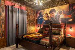 Rest in a magical wizard themed bedroom with a cozy four poster bed, library wall design, warm lighting, rich colors, and detailed ceiling decor, creating a fun and immersive space for vacation.