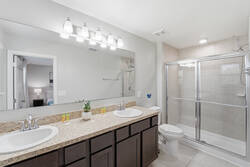 Refresh in a bright bathroom with double sinks, granite counter, large mirror, glass shower, soft lighting, and clean finishes, creating a practical and comfortable space for your vacation.