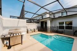 Relax in a private screened pool area with sparkling water, outdoor seating, hanging chair, BBQ grill, and open sky views, perfect for swimming and family moments during vacation.