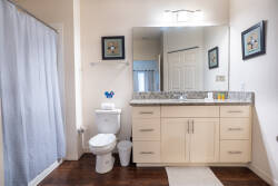 Experience a beautifully designed bathroom with a sleek granite countertop and modern cabinetry. Enjoy soft lighting, decorative artwork, and easy access to a refreshing shower for a bright and inviting experience.