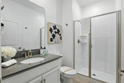 Enjoy a stylish bathroom with sleek gray countertops and a spacious walk-in shower, offering both freshness and functionality. Modern fixtures and subtle floral artwork enhance your comfort for a delightful stay.