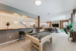 Discover our inviting game room with a stylish pool table, modern bar seating, and lively greenery. Enjoy the natural light from large windows, creating an ideal space for fun and relaxation with friends and family.
