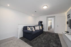 This cozy lounge area features a plush navy sofa adorned with decorative pillows, inviting you to unwind. The soft carpet underfoot and warm lighting create a welcoming atmosphere, perfect for relaxing after a day of exploration.