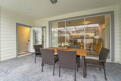 Relax on the spacious patio featuring a stylish wooden dining table ideal for al fresco meals with friends or family. Surrounded by modern wicker chairs, this bright outdoor oasis beautifully blends indoor and outdoor living.