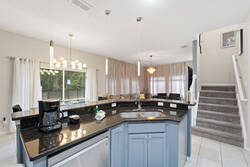 This stylish kitchen boasts granite countertops and soft blue cabinetry, creating a fresh atmosphere. Large windows let in natural light, and chic pendant lighting adds a modern touch, making it ideal for your culinary adventures.