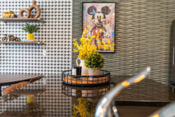 Enjoy a stylish kitchen featuring a striking houndstooth accent wall, sleek dark countertops, and cheerful fresh flowers, all enhanced by playful Mickey Mouse artwork that invites you to relax and fully enjoy your stay.