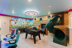 Discover a lively game room filled with a foosball table, colorful seating, and whimsical wall art that ignites creativity. Enjoy the sleek slide, adding a unique twist to an inviting space perfect for relaxation and fun.