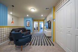Enter a lively living area where striking blue walls meet cheerful yellow accents. A stylish patterned rug defines the space, and inviting seating creates a cozy atmosphere perfect for relaxation and unwinding.