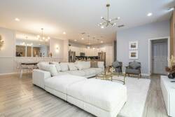 Step into a spacious living area featuring a plush, L-shaped sofa and sleek, modern lighting that sets a welcoming tone. The soft, neutral palette enhances the open layout, while chic accents add a touch of sophistication.