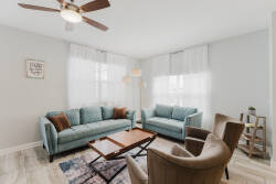 This bright living room welcomes you with soft blue sofas and a chic wooden coffee table, while natural light filters through sheer curtains, creating a cozy space to unwind after your day of adventure.