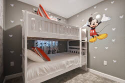 This vibrant children's room has a cozy white bunk bed with playful orange accents, perfect for sleepovers. With a delightful Mickey Mouse theme, it creates a cheerful and fun escape for young guests to enjoy.