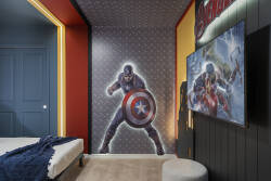 Rest in a bold superhero themed bedroom with two comfortable beds, vibrant wall art, red accents, and fun lighting. The dramatic decor creates an exciting space for kids and fans to enjoy during their vacation.