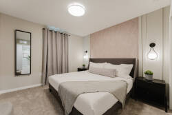 Welcome to your tranquil bedroom, where a plush bed with soft linens and a cozy throw awaits. The warm tones and stylish decor create a soothing atmosphere, perfect for restful nights and relaxation. Enjoy your stay!