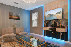 Relax in a stylish living area with a chic glass coffee table and plush seating. The striking hexagonal accent wall with integrated lighting provides a modern backdrop for unwinding after your adventures.