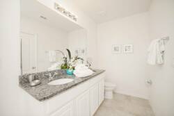 This bright and airy bathroom boasts a sleek granite countertop and crisp white cabinetry for a fresh ambiance. With subtle decor and plush towels, it elevates your daily routine into a more luxurious experience.