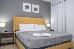 Unwind in this stylish bedroom with a plush orange headboard that brightens the calming gray walls. The soft bedside lamp lighting creates a cozy atmosphere, perfect for relaxing after a day of exploring.