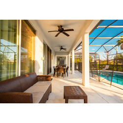 Relax on a covered lanai with wicker seating, ceiling fans, an outdoor dining table, and direct views of the private screened pool. Warm sunlight and open patio space create a comfortable spot for meals and family time.