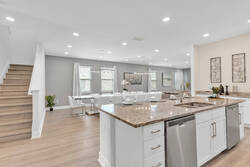 Gather in a bright open space with a modern kitchen, granite island, stainless steel appliances, dining area, soft curtains, wood flooring, and easy access to the living room.