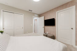 Experience restful nights in this cozy bedroom featuring soft, neutral tones and plush bedding. The sleek wall-mounted TV adds a modern touch, while the textured accent wall creates a warm atmosphere, perfect for winding down.