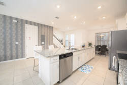 Experience a stylish kitchen featuring elegant white cabinets and beautiful granite countertops, enhanced by charming wallpaper.