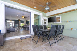 Step outside to a spacious dining area with sleek black chairs, perfect for alfresco meals. The warm wooden ceiling and cool green walls create a welcoming vibe, while the seamless indoor-outdoor flow enhances your relaxation.