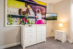 Enjoy a cozy atmosphere with a stunning large artwork of a girl and her horse, soft gray walls, and plush carpet. The white dresser and bedside table add a fresh touch, creating the perfect space to relax and unwind.