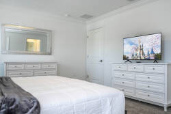Bright and airy, this bedroom features a cozy white bedspread complemented by charming light wood furniture. A large mirror reflects the soft natural light, while the flat-screen TV invites you to unwind after a day of adventure.