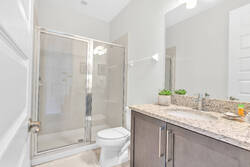 Freshen up in a bright modern bathroom with a granite vanity, large mirror, glass shower, soft neutral tones, and simple decor, creating a clean and comfortable space.