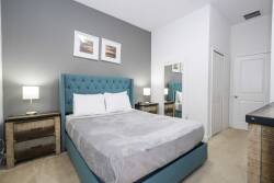 Step into a stylish bedroom featuring a plush turquoise headboard complemented by sleek nightstands. The soft, neutral carpet enhances the cozy atmosphere, while framed artwork adds a touch of character to the inviting walls.
