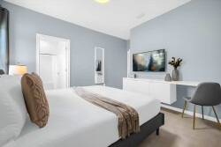 Enjoy peaceful nights in this beautifully designed bedroom with a plush bed and cozy throw. The serene blue walls and stylish white furniture create a calming vibe, while plenty of natural light adds to the welcoming atmosphere.