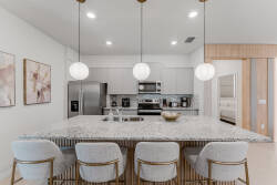 Step into this stylish kitchen featuring a striking granite island surrounded by plush, upholstered bar stools. The sleek stainless steel appliances and warm wood accents create a harmonious blend, perfect for culinary adventures.