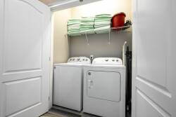 Enjoy the convenience of a well-equipped laundry area with a sleek washer and dryer, along with neatly stacked green towels, ensuring a clean and organized space for a hassle-free stay focused on your relaxation.