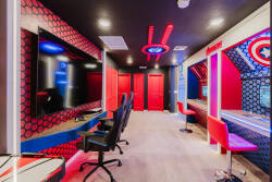 Experience a lively entertainment room with bold red and blue decor, a large flat-screen TV, and stylish gaming chairs. This fun superhero theme is ideal for thrilling movie nights or gaming marathons with friends.