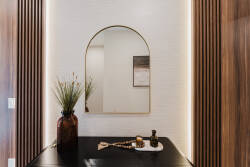 Step into a stylish entryway that combines natural textures with contemporary design. The warm wood paneling contrasts beautifully with the light wall, while a chic mirror and elegant vase create a welcoming first impression.