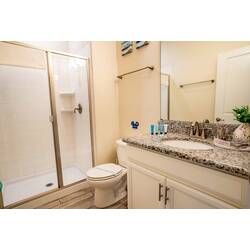 Experience a beautifully designed bathroom with a sleek granite countertop and clean white cabinetry. The spacious glass shower invites relaxation, while soft lighting sets a welcoming atmosphere for your daily routines.
